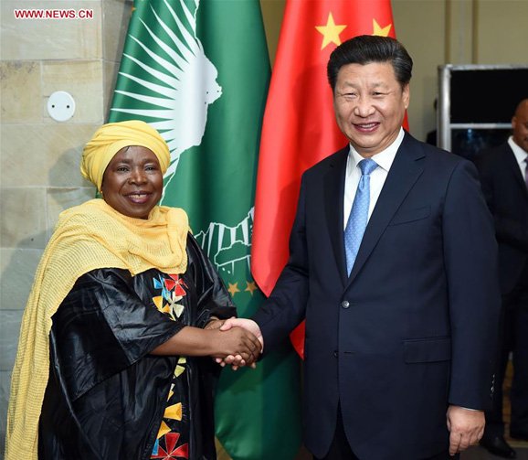 Chinese President Xi Jinping shakes hands with an African Union official in front of the African Union and Chinese flags.
